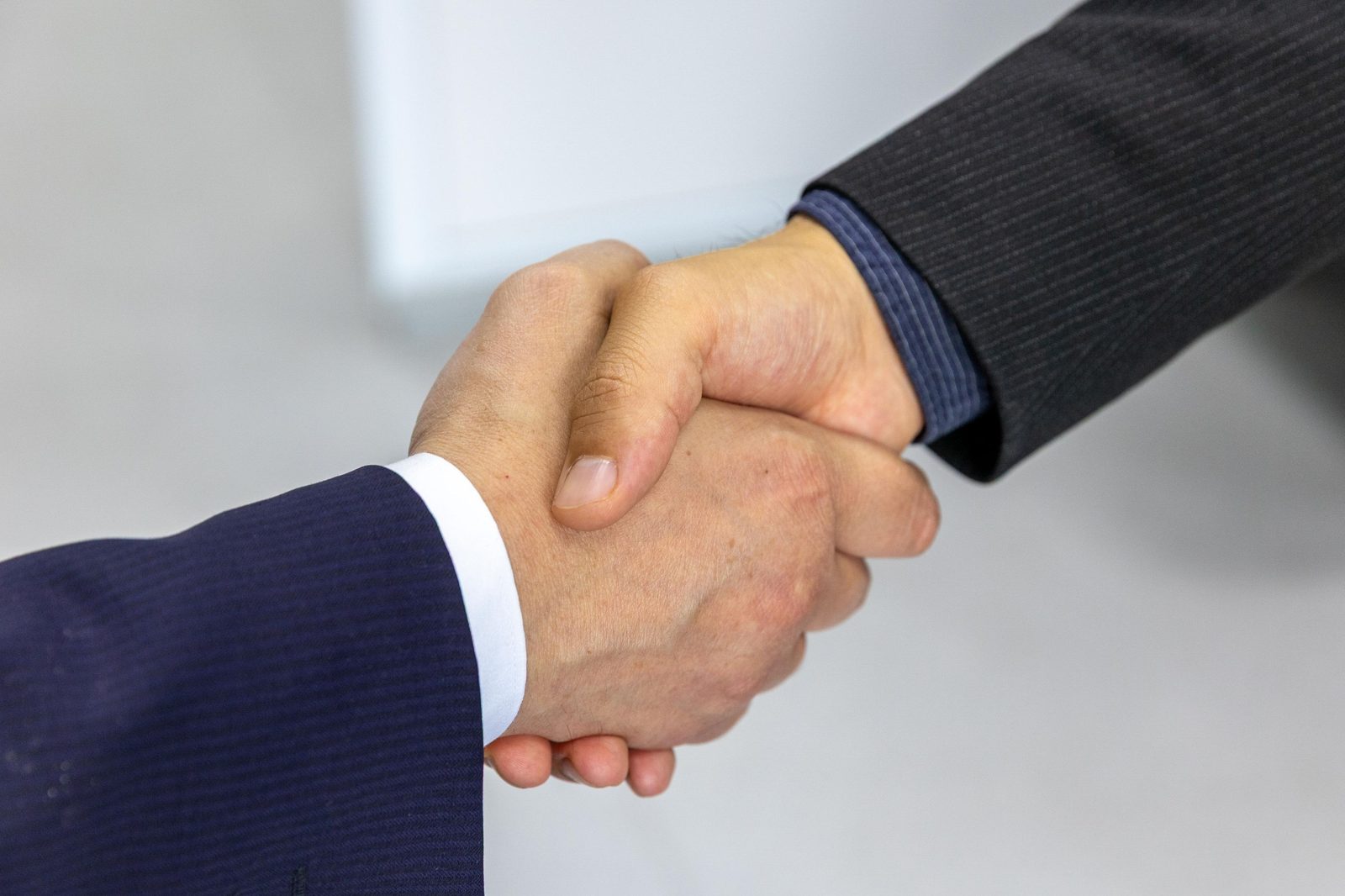 Two people in business suits shaking hands to close a deal