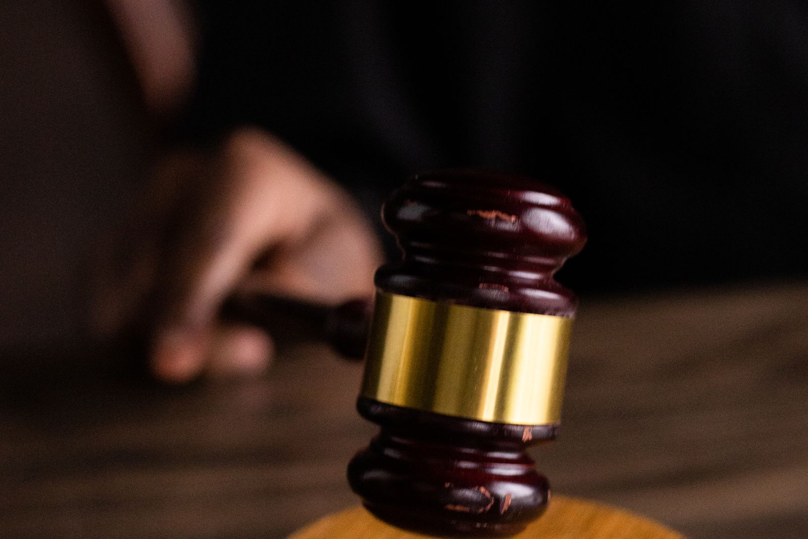 A judge's gavel resting on its sound block, with a hand blurred in the background