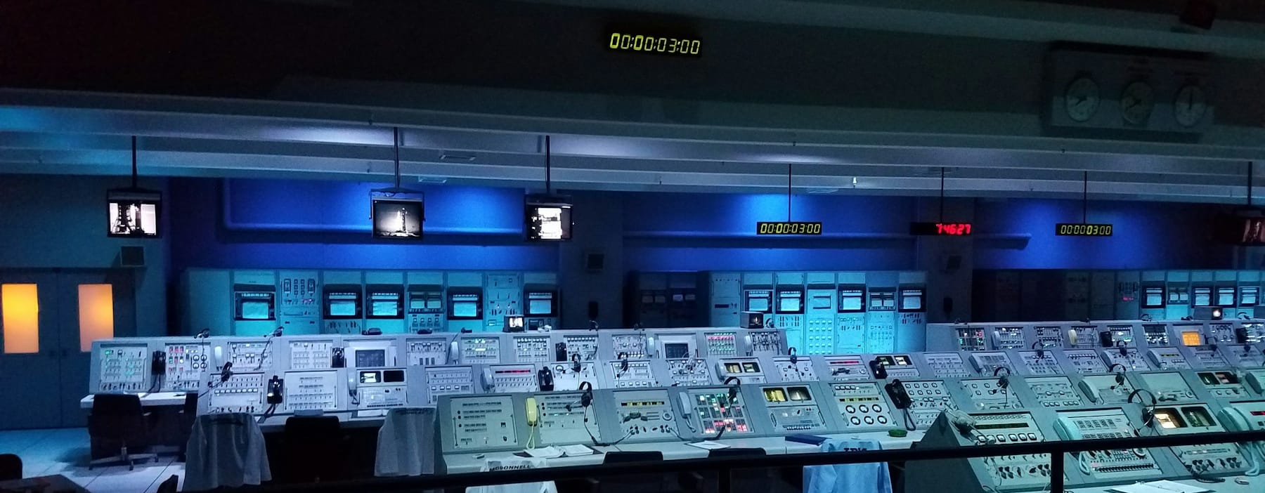 Rows of illuminated monitoring consoles in a darkened control room
