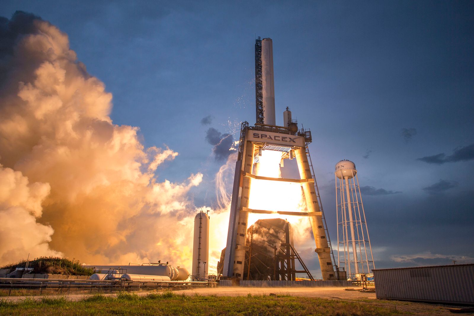 A rocket lifting off in a burst of flame and smoke against a dusk sky