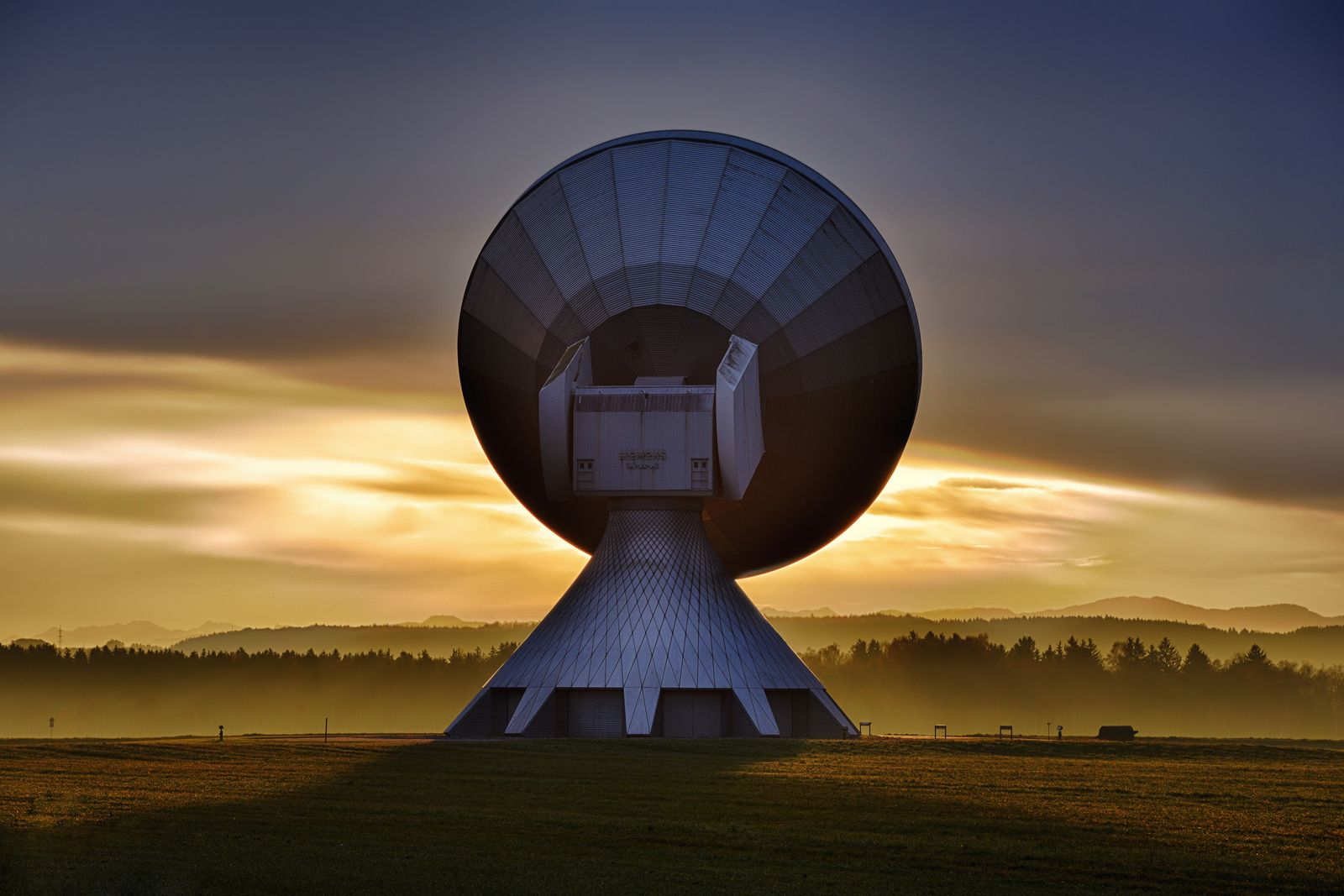 A white satellite dish silhouetted against a colorful sunset sky